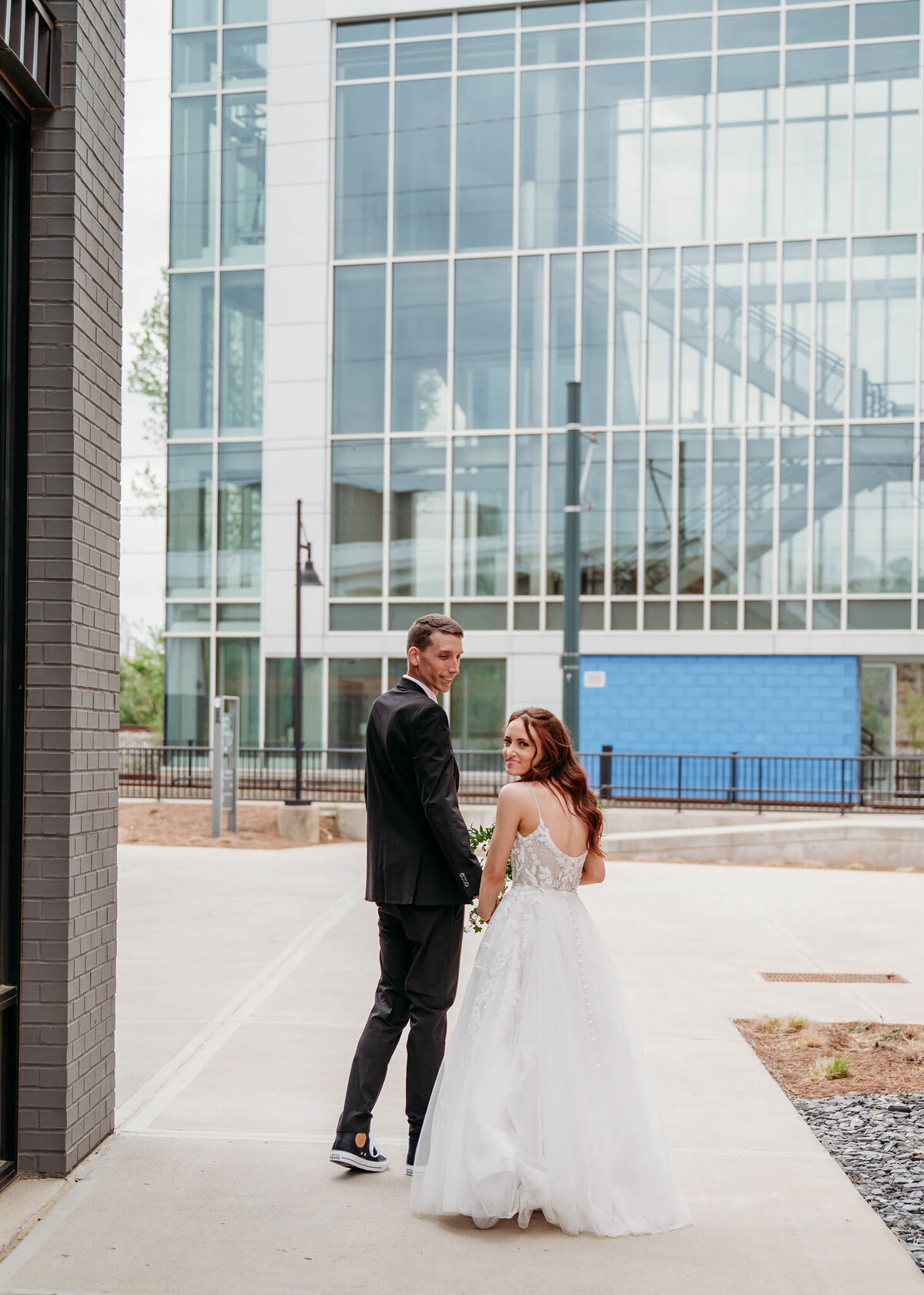 Bride and groom walking hand in hand near modern building