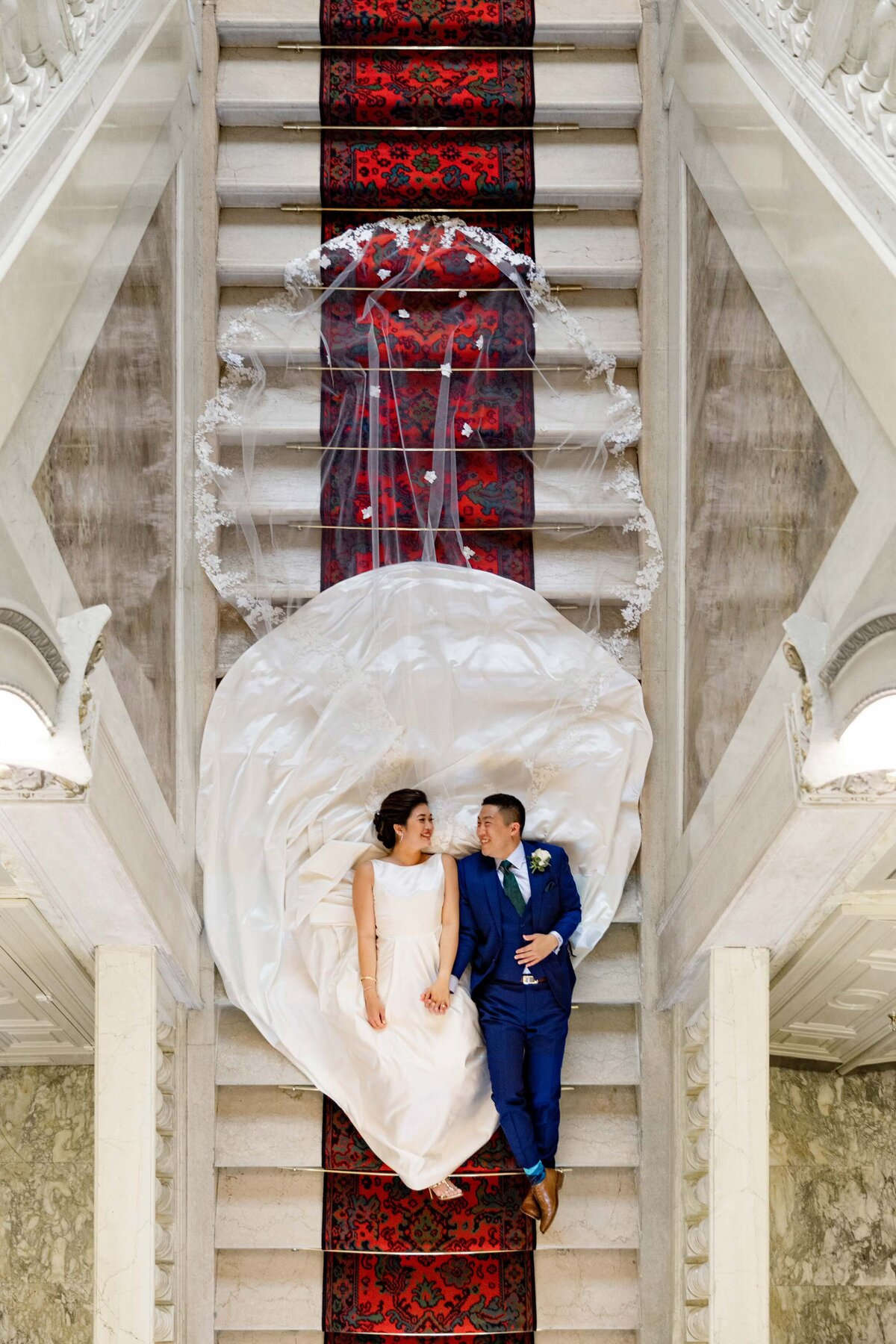 Image from above of a couple lying down on a staircase.