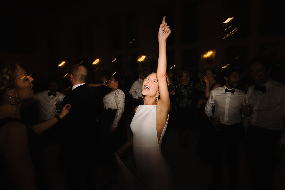 Bride puts her hand in the air to while she dances at her wedding