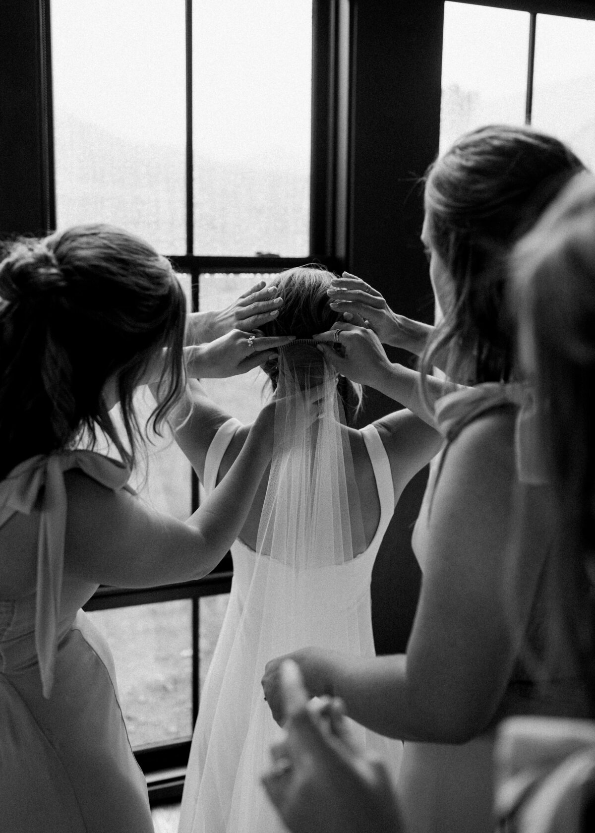 Virginia wedding photographer captures a great moment where the bridesmaids are helping the bride secure her veil