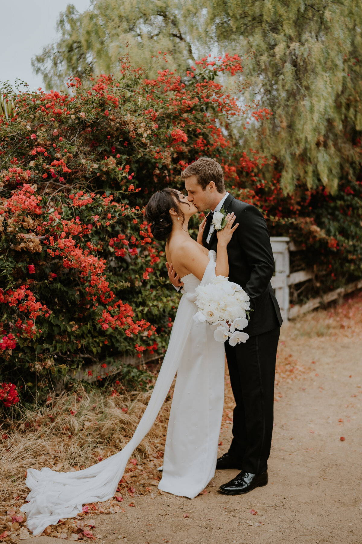 Bride kisses groom in front of flowers