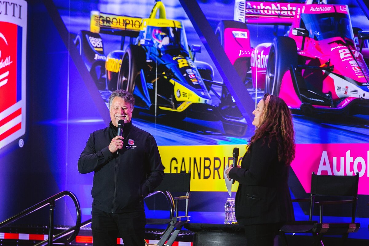 a-speaker-and-a-professional-discuss-motorsports-on-stage-at-an-event-in-indianapolis-celebrating-the-excitement-of-racing-in-the-month-of-may