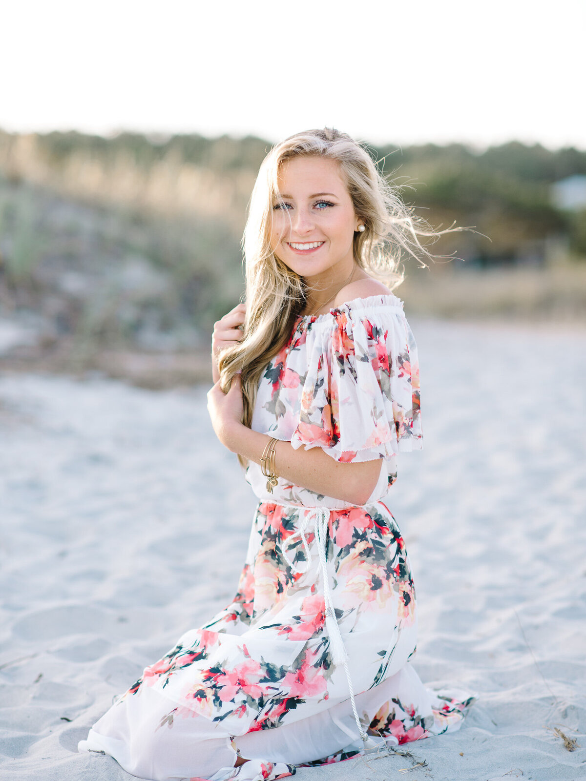 Senior girl in white floral dress posing at Kiawah Island beach during golden hour