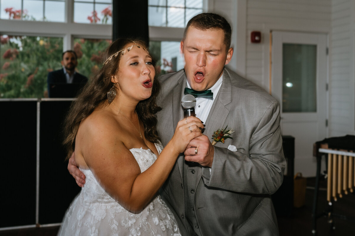Bride and groom sing into microphone at reception