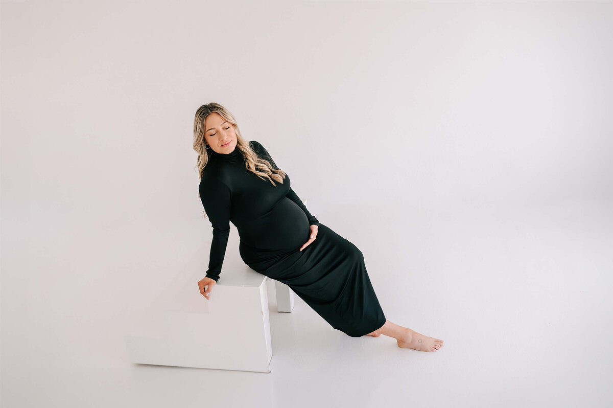 pregnant mom leaning on white step enjoying Joplin Maternity photography