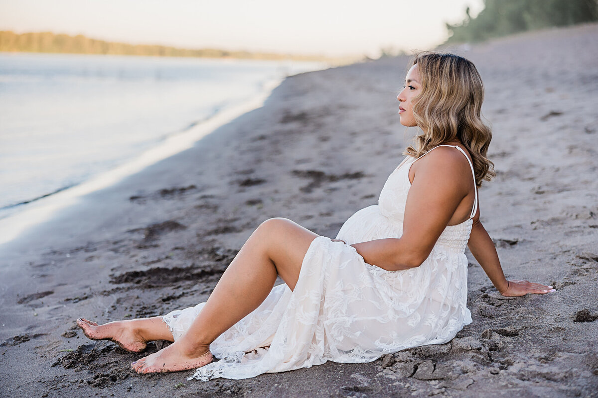 mom in white dress on sandy beach for maternity photography with ann marshall photography in portland oregon