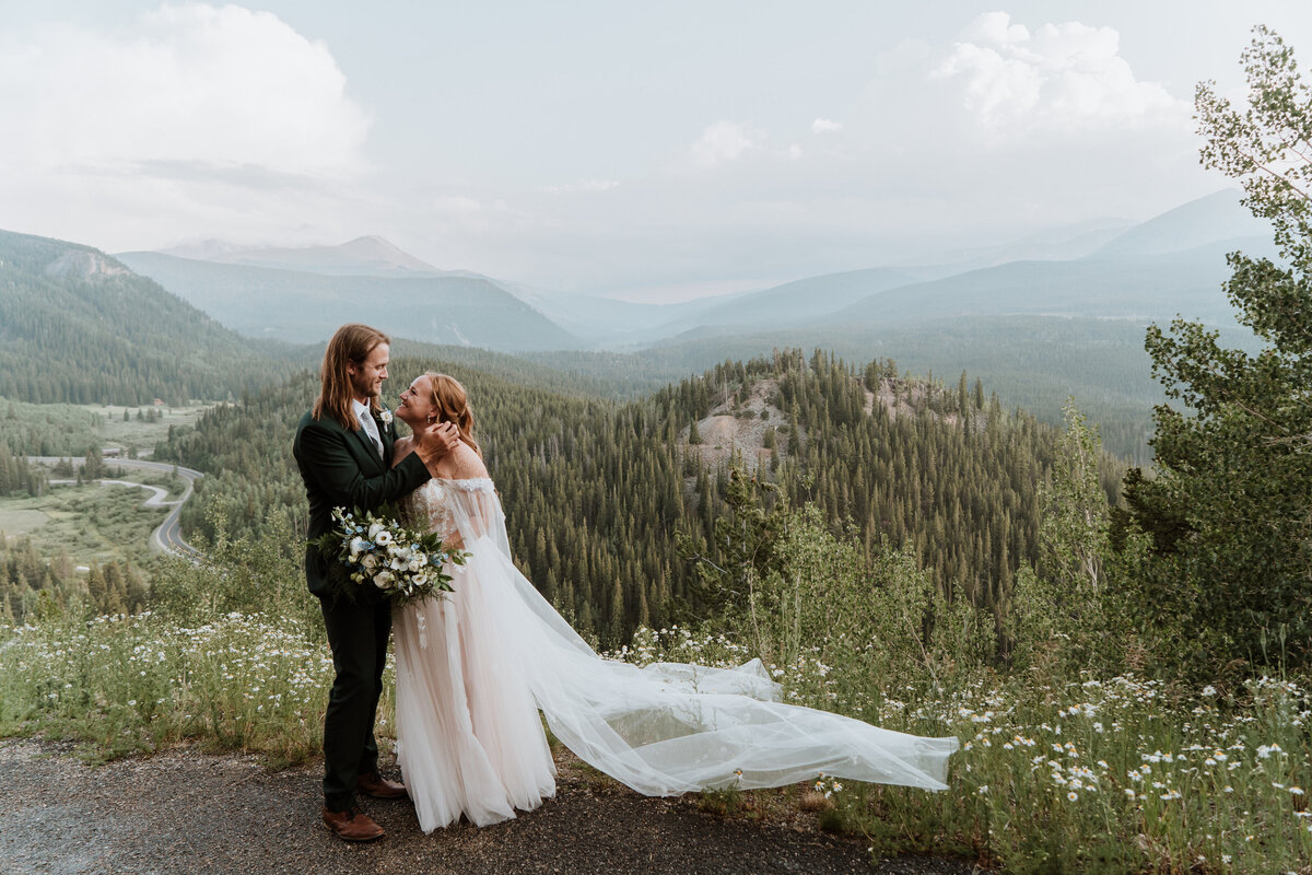 Romantic newlywed moment with sweeping veil over mountain landscape in Breckenridge.