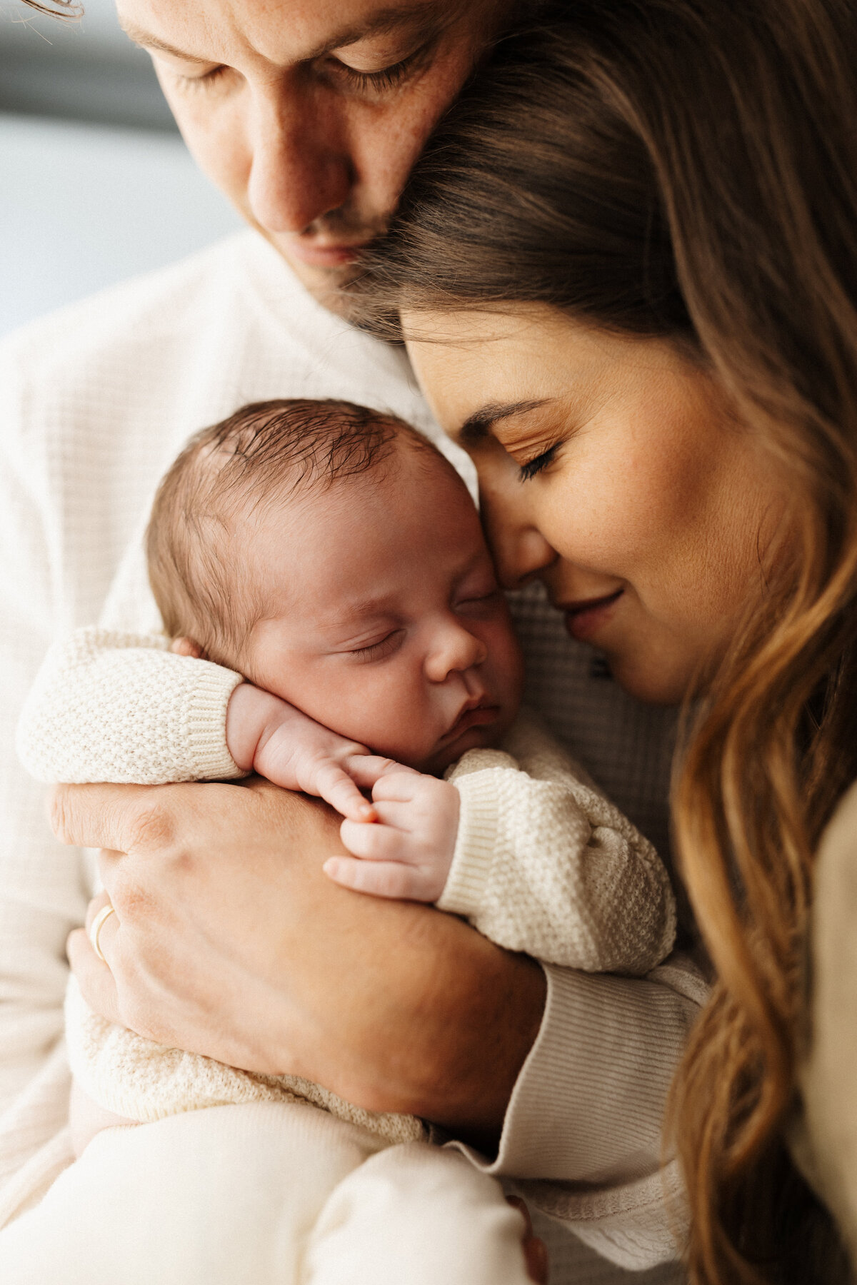 A mother and father holding their newborn baby during a newborn photoshoot in christchurch with newborn photographer lucy jane