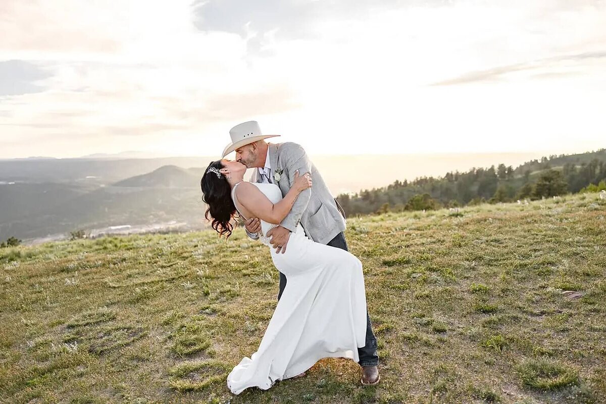 Colorado wedding photography of groom dipping bride and kissing with mountains in the background
