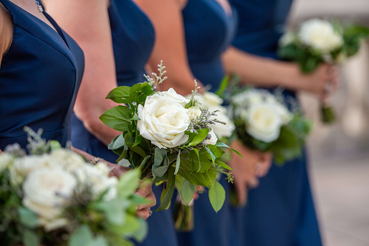 a closeup photo of elegant navy bridesmaid dresses and their bouquets as part of a Chateau Laurier wedding in Ottawa.  Photographed by Ottawa wedding photographer JEMMAN Photography