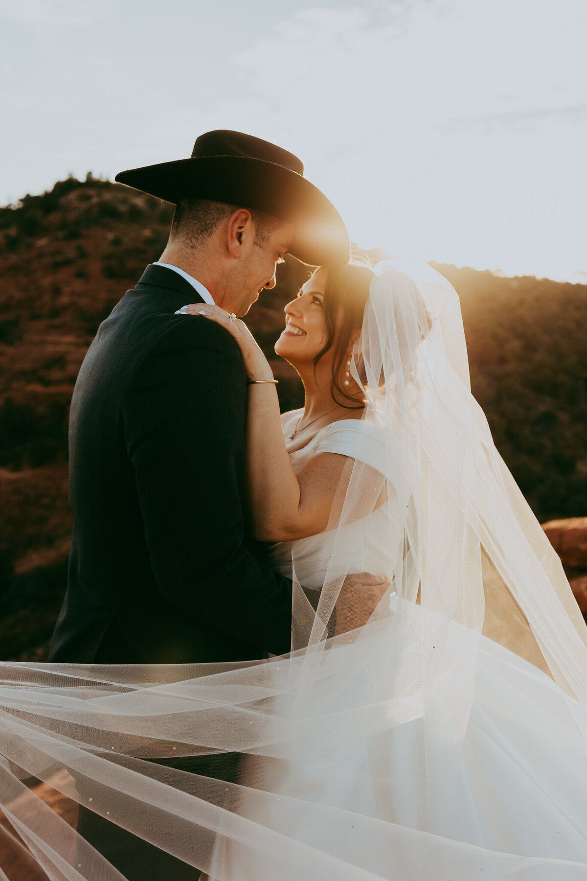 bride and groom stand together at sunset