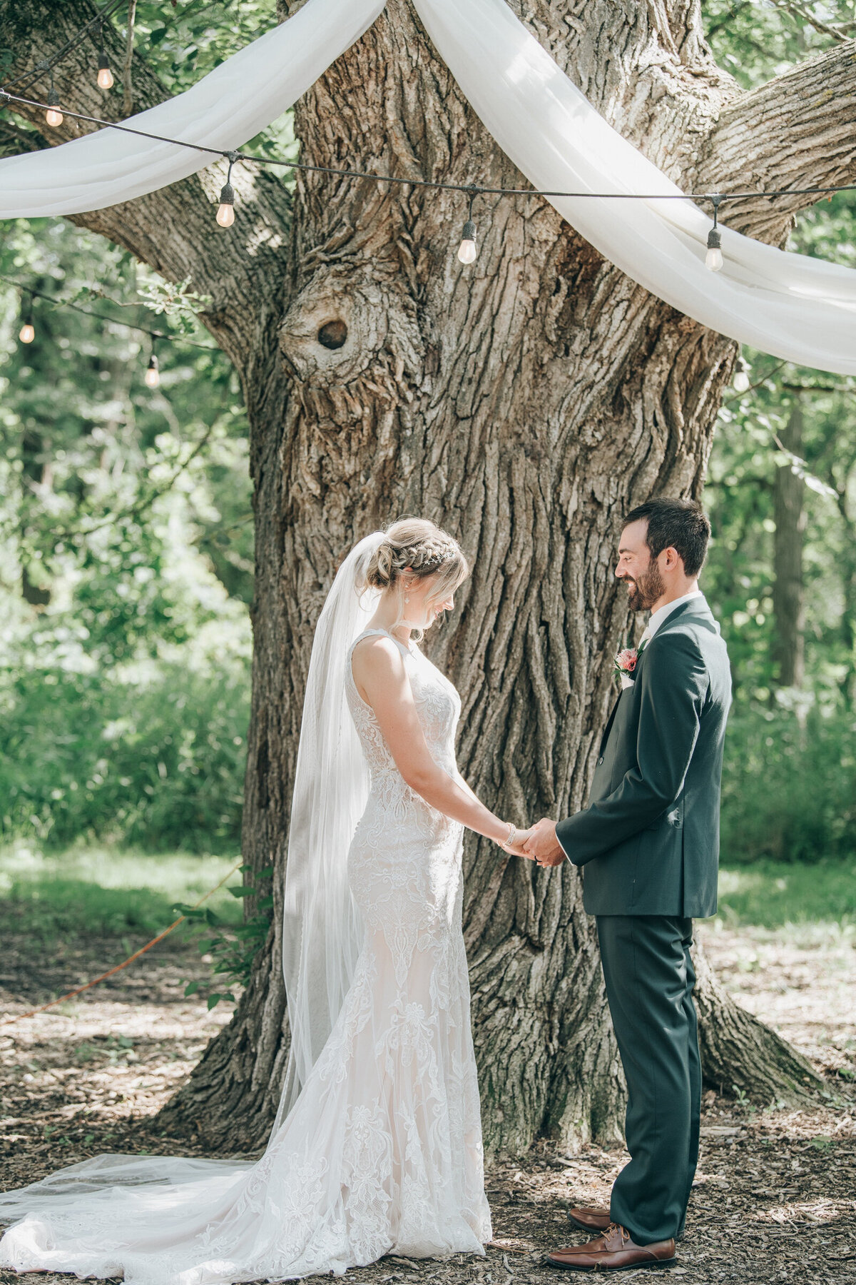 Bride and groom saying their vows under a willow tree during their outdoor Summer wedding ceremony