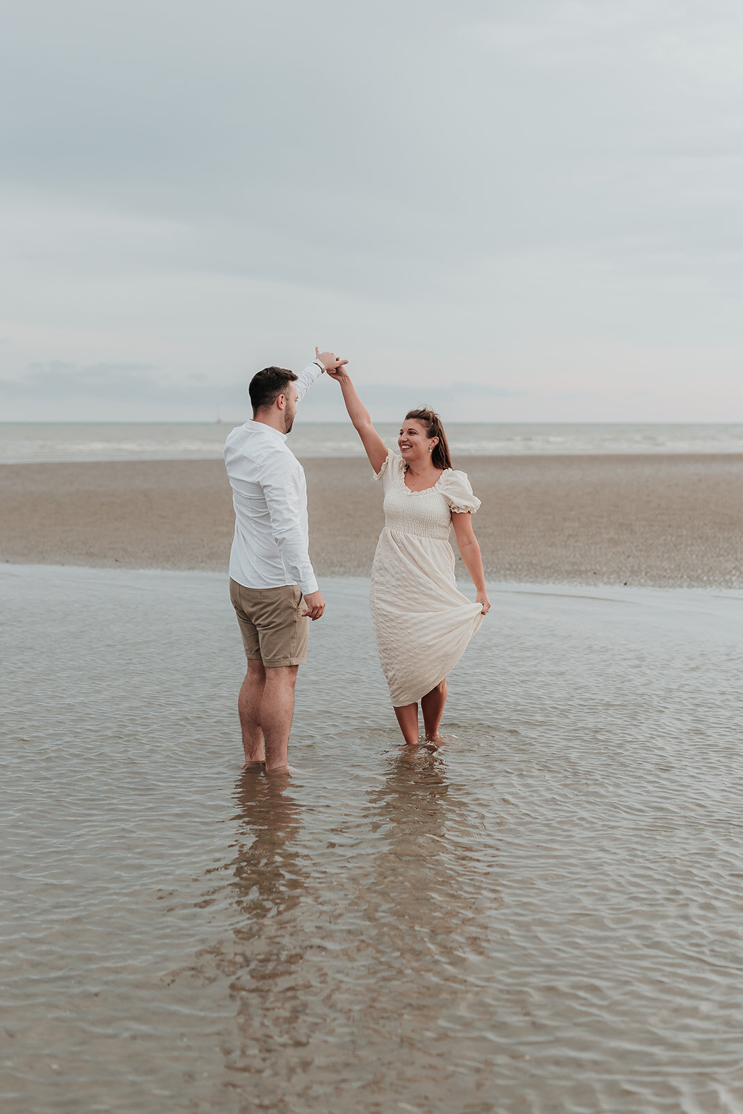 Couple slowly dance in the shallow sea on the beach at Camber Sands, Rye