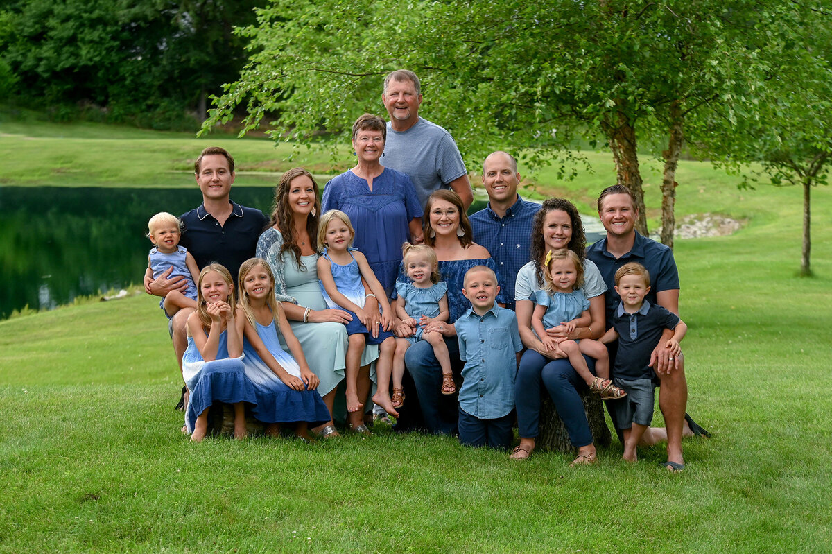 An extended family in blue sits together by a pond