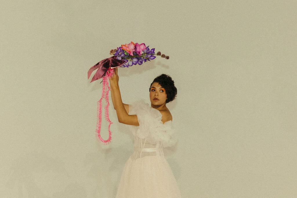 A person in a wedding dress holding up a bouquet of flowers.