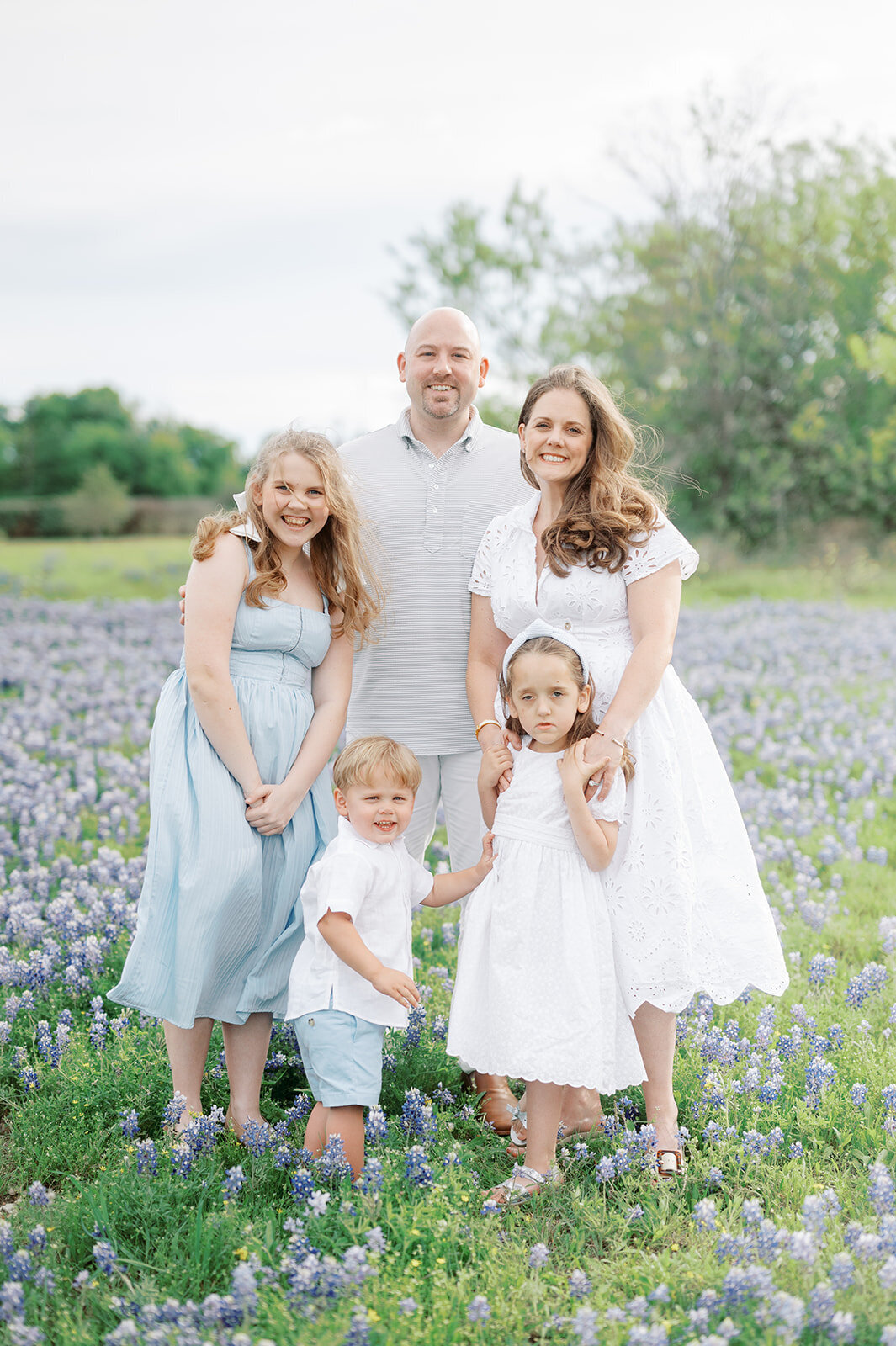 A heartwarming portrait of a mother and her daughters walking hand-in-hand through a sea of bluebonnets in Dallas.
