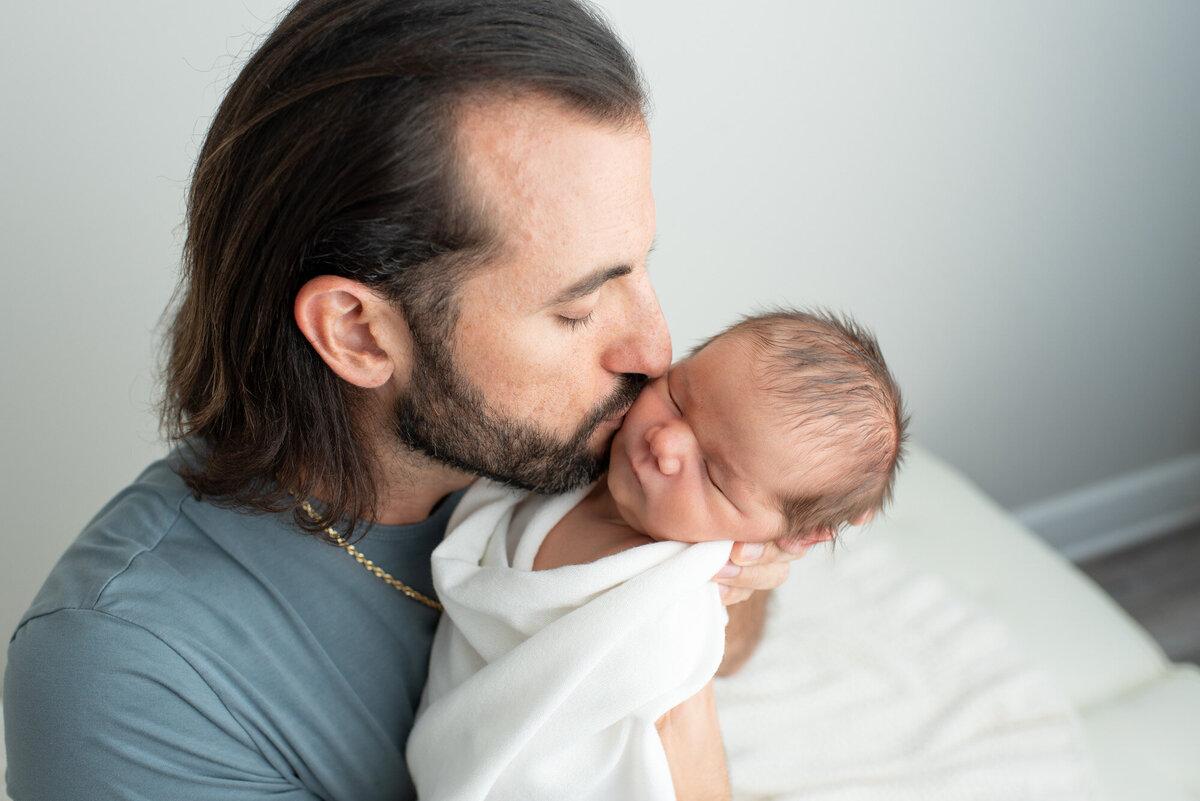 dad kissing newborn on cheek