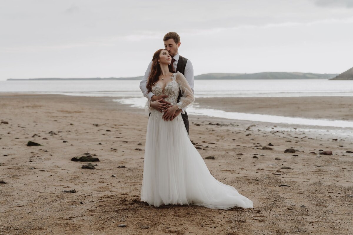 Couple standing on a big open beach having their couple portraits