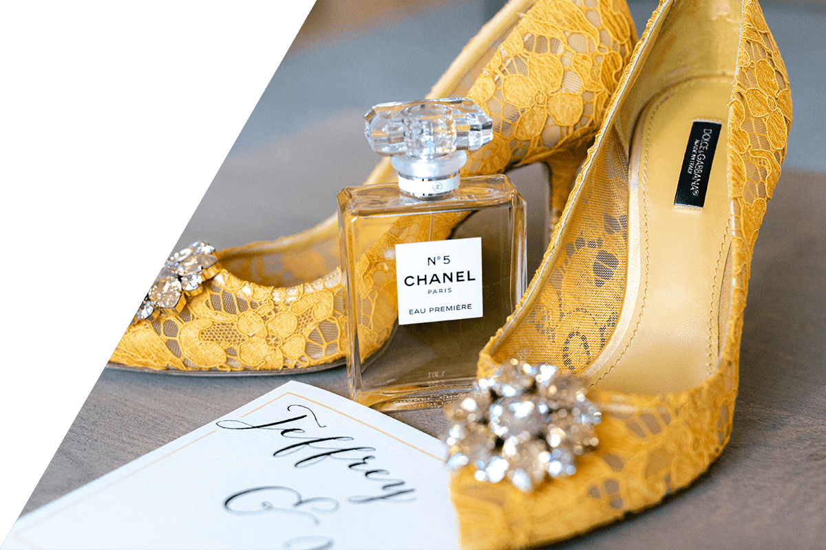 Detailfoto van gele trouwschoenen van Dolce & Gabbana en parfum van Chanel no 5 en stationery trouwkaart op een italiaanse bruiloft
