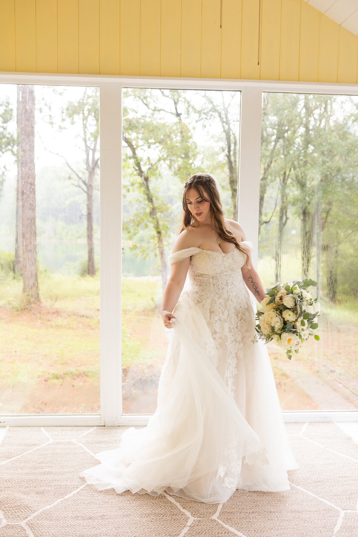 bride holding dress and white floral bouquet at Camp Retreat. in Baker Florida by Florida wedding photographer Amanda Richardson Photography
