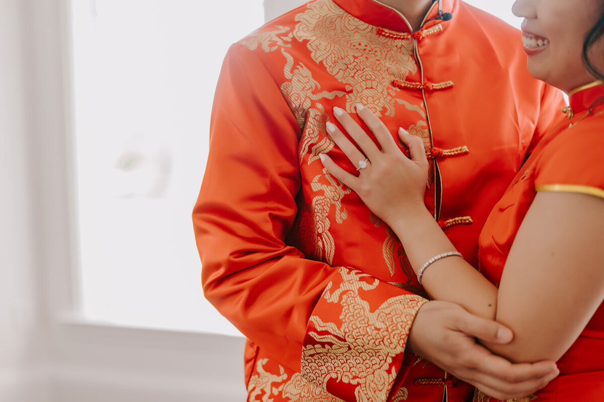 Close-up of couple’s hands in traditional red attire