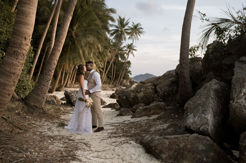 Un couple s’embrasse au coucher du soleil sur une plage de Koh Samui, en Thaïlande, pour leur mariage intimiste en bord de mer.