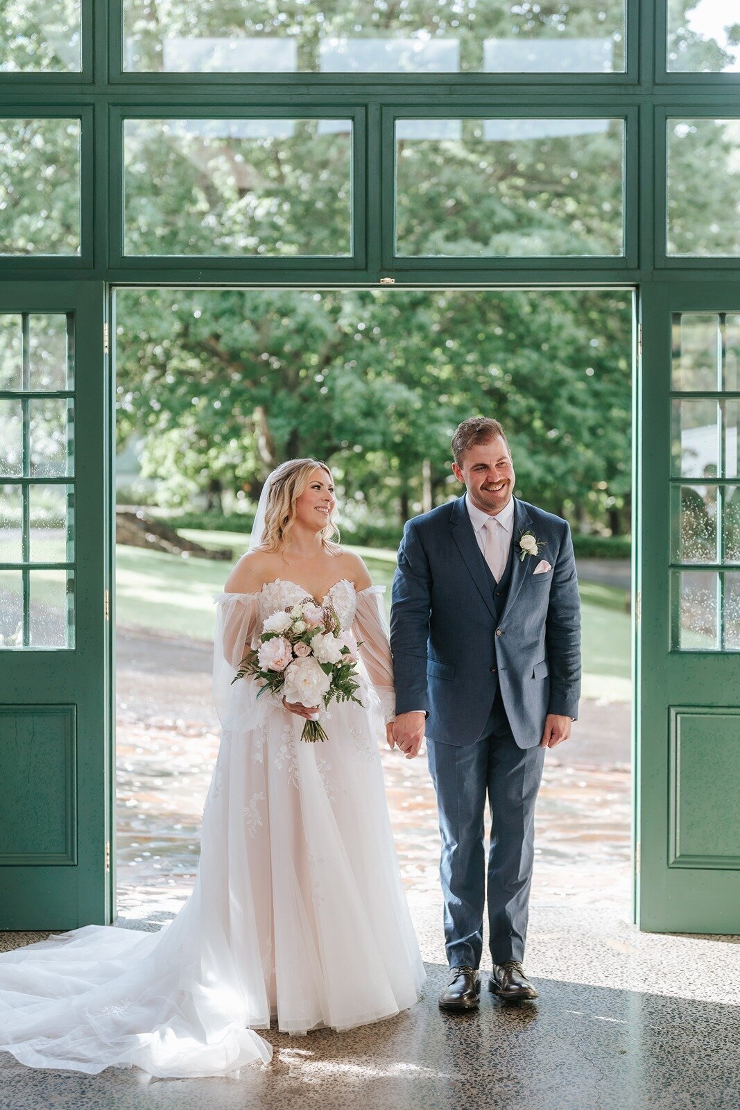 Bride in white dress and groom in blue suit getting married at Flowerdale Estate