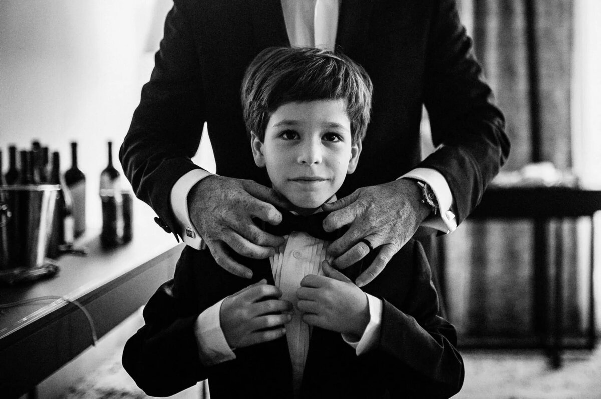 A man helping a boy with his bow tie.