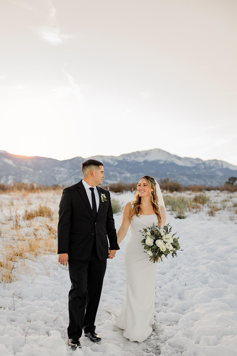 Bride and groom holding hands and walking with blue mountains backdrop.