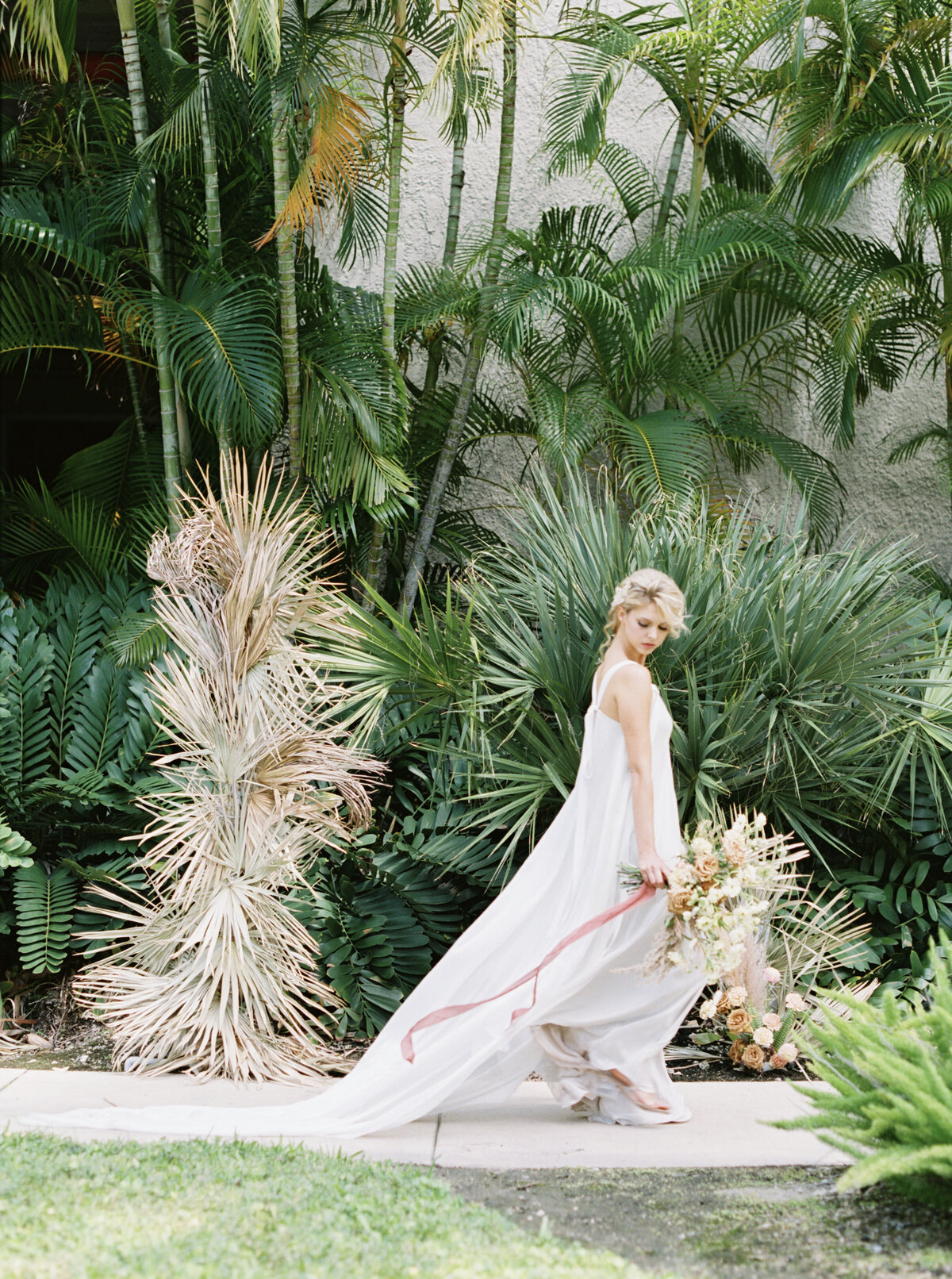 Blonde Bride turns away and walks, dress flowing.