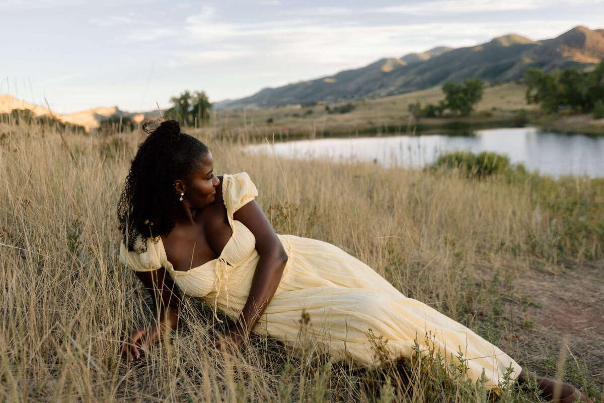 Woman laying in a field with rocky mountains in the background