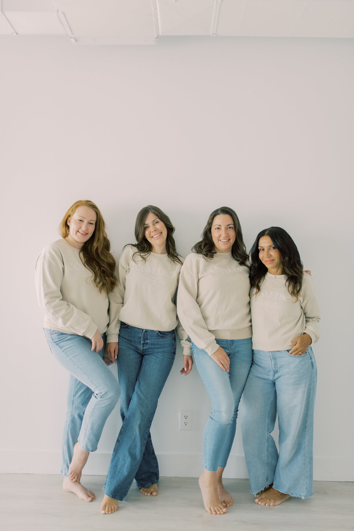 Team standing side by side in branded sweatshirts and jeans—relaxed and modern clinic portrait
