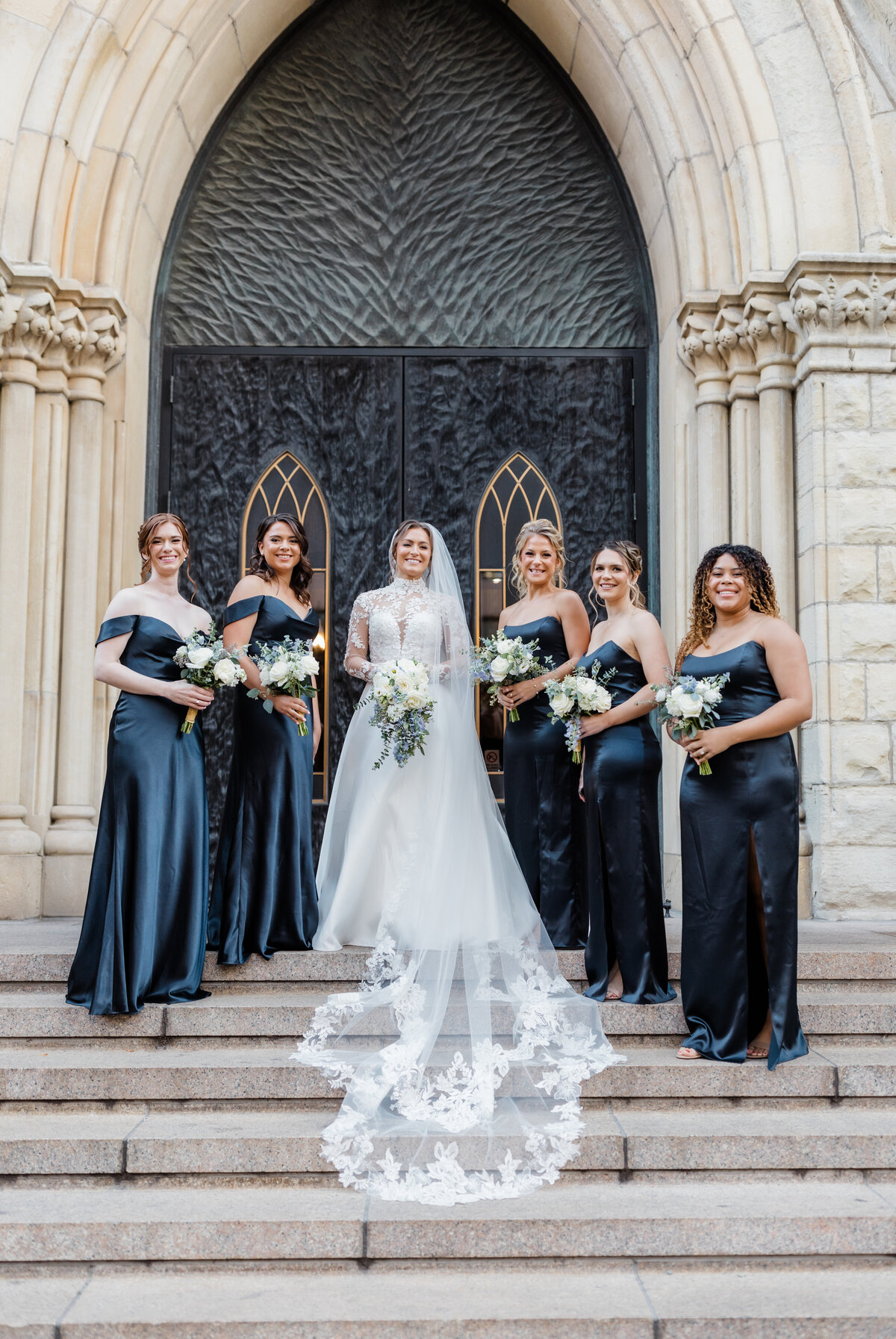 Bride posing with her bridesmaids in navy dresses outside a stunning South Bend wedding venue.