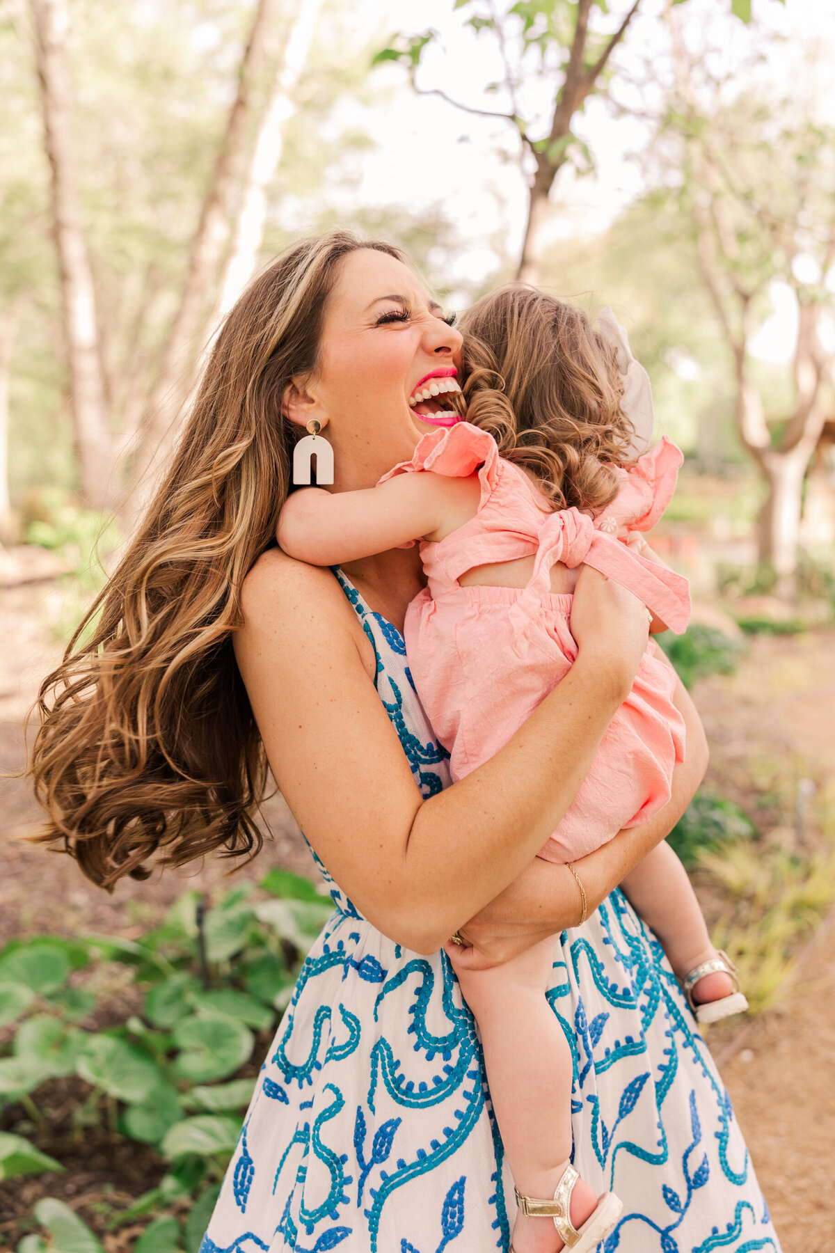 mother-hugging-2-year-old-daughter-in-a-park