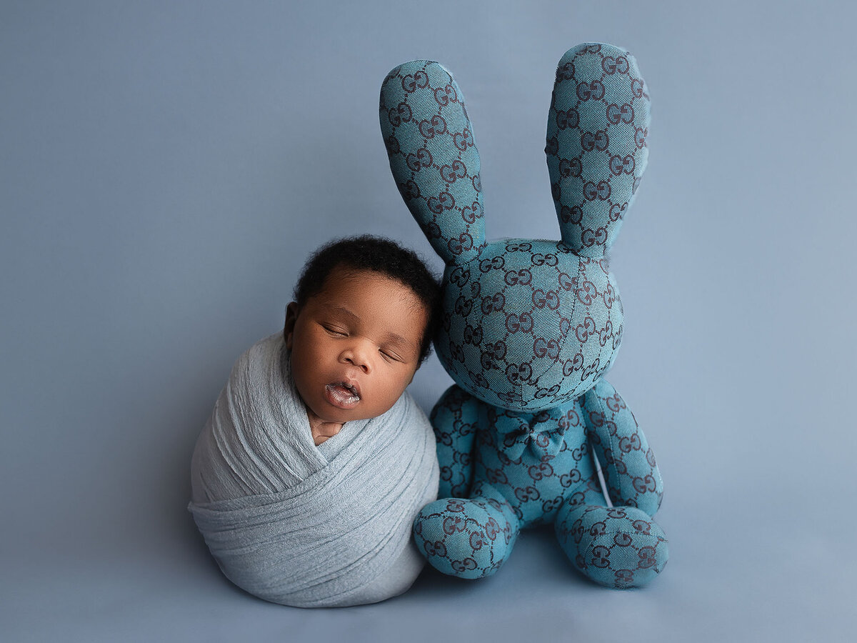 cute baby rests up against his favourite toy during hamilton newborn photoshoot