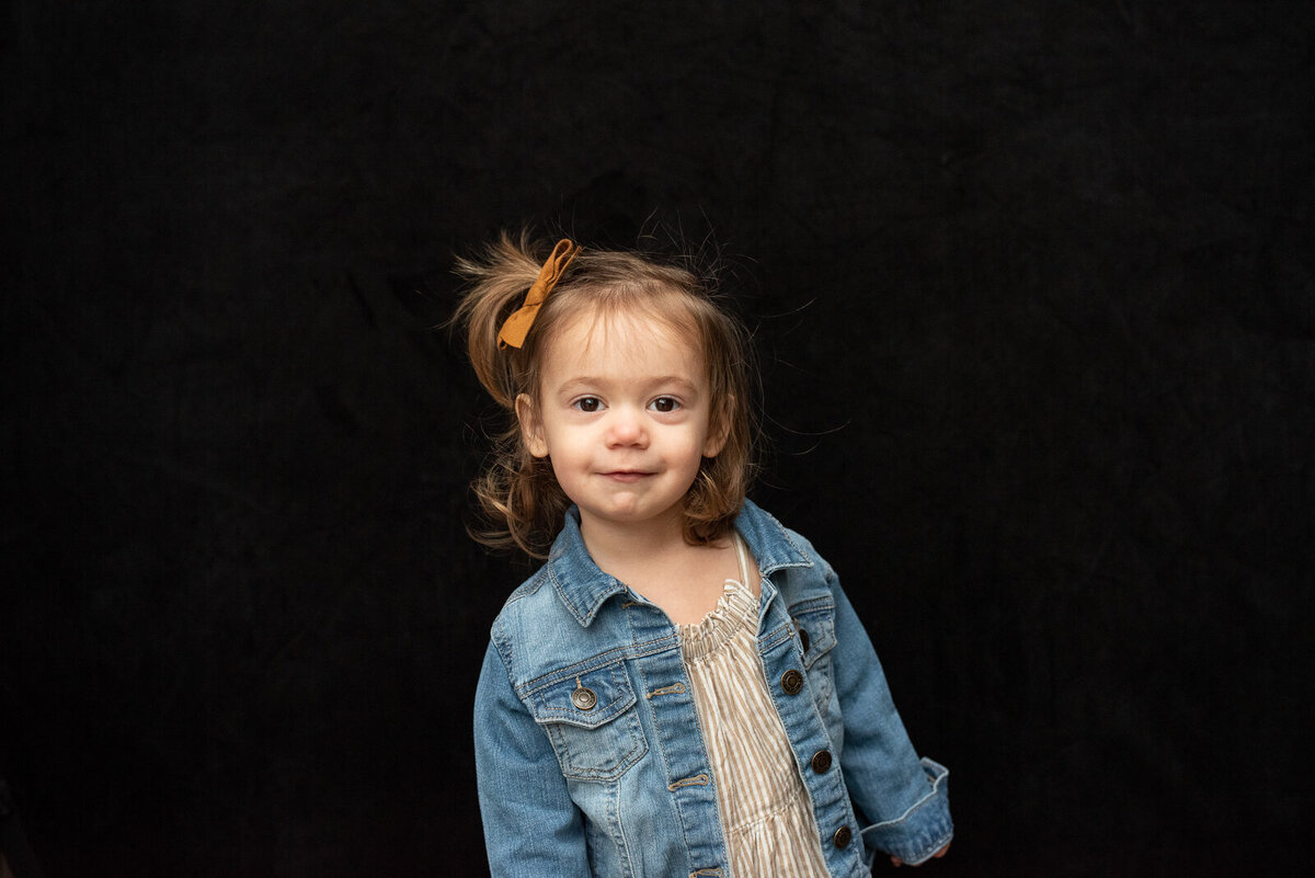 Young girl with small ponytail wearing a denim jacket and striped beige dress for kids personality portraits in Tacoma
