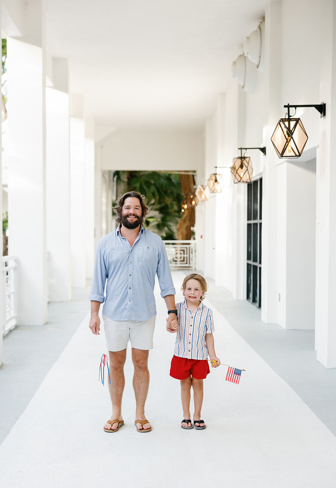 A father and young son pose in a stunning white hallway during a Florida Keys family photography session with Claudia Amalia.