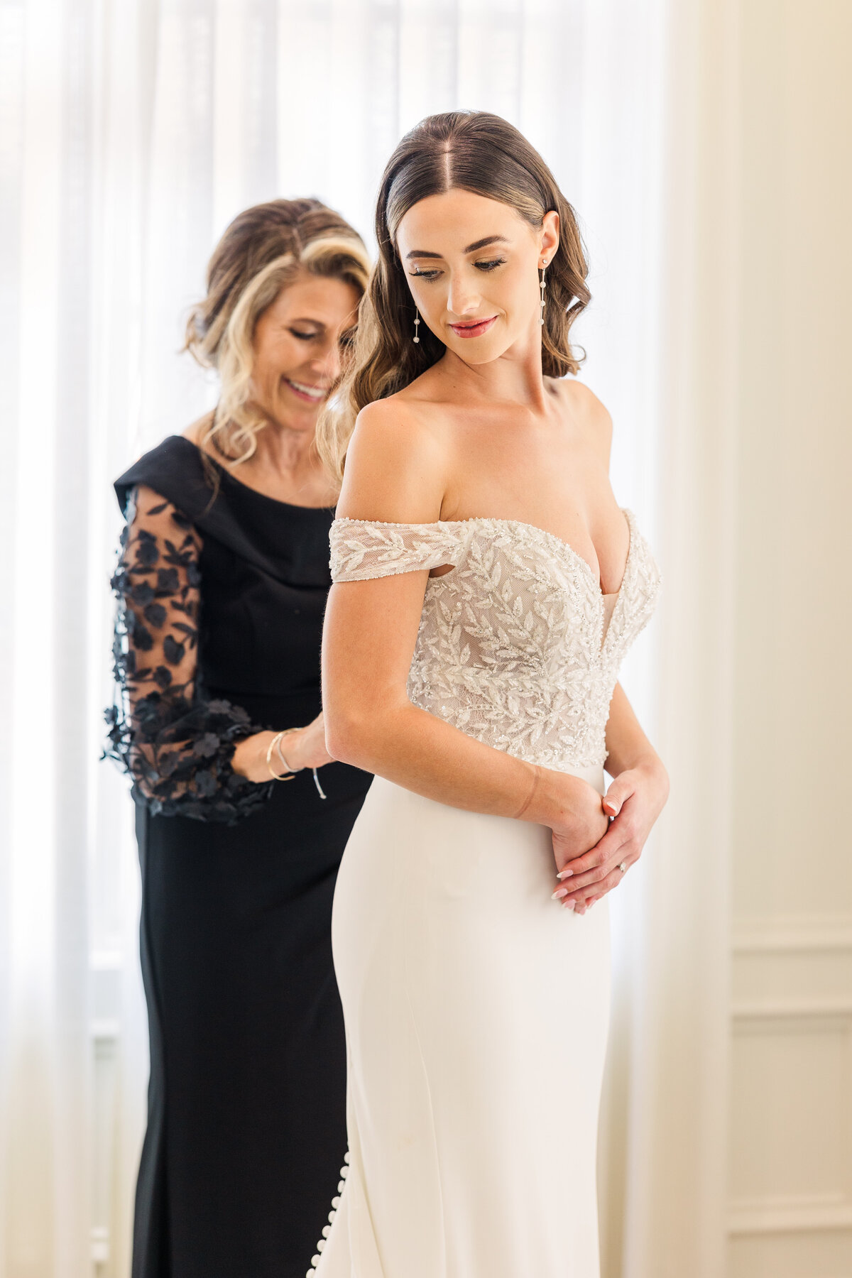 Tender moment between mother and daughter as they prepare for the ceremony, with the bride in a leaf-embroidered gown and the mother in a black lace sleeve dress, taken in Westlake.