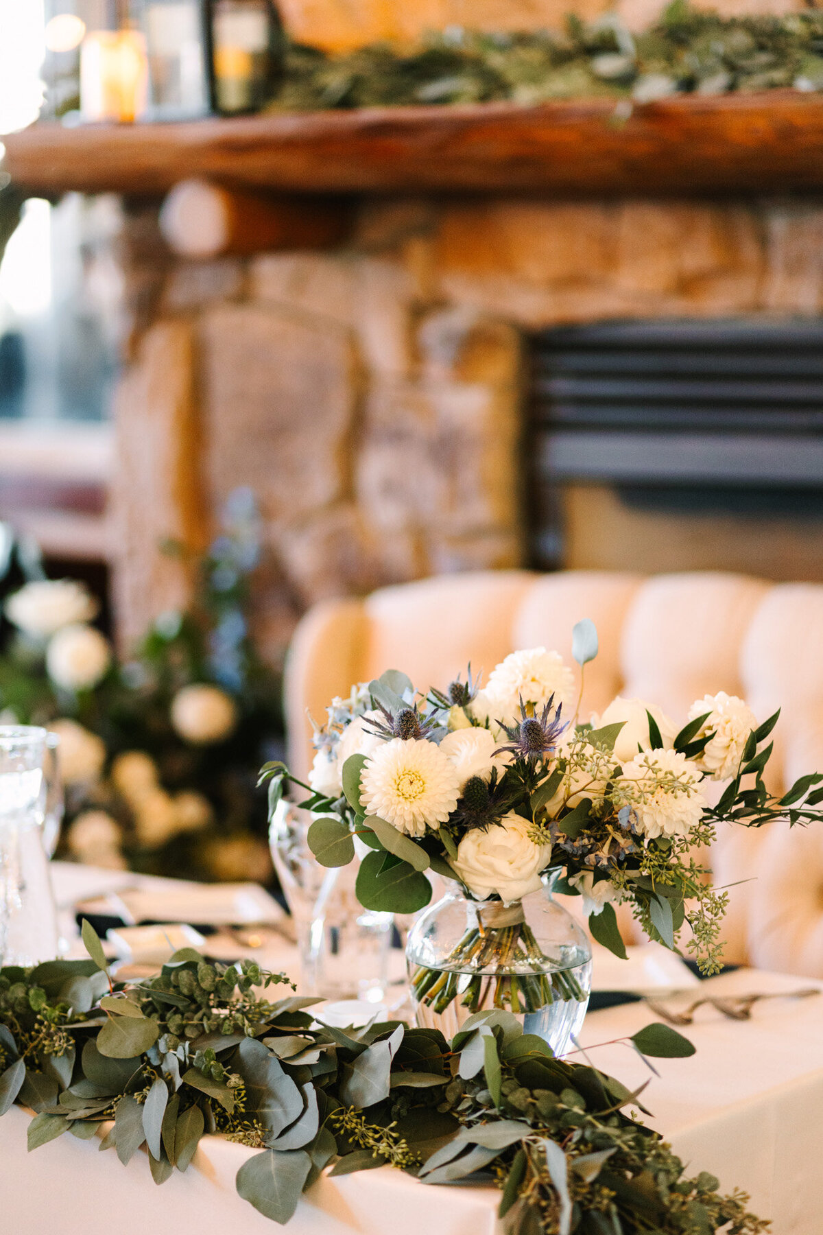 Elegant wedding reception table set-up that has florals submerged in a transparent vase with water centerpiece