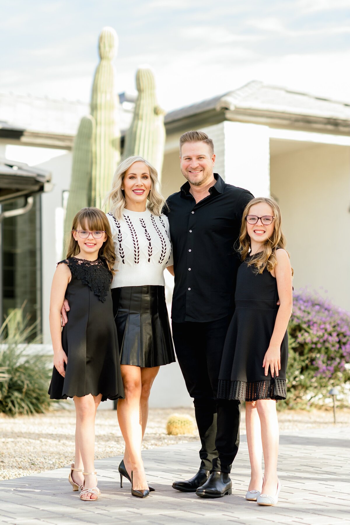 family of four standing in front of their house in north scottsdale psoing for photo