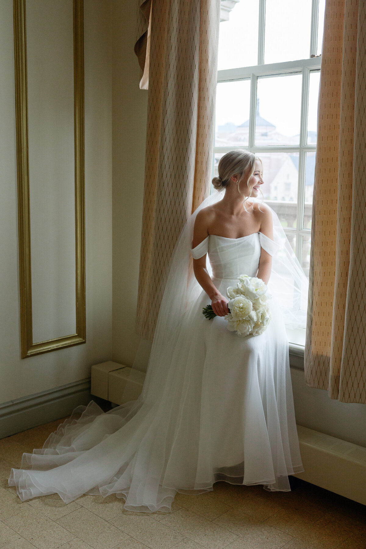A beautiful solo portrait of the bride looking out the window at The Memorial Union on her wedding day, capturing a moment of reflection and anticipation amidst the iconic architecture.