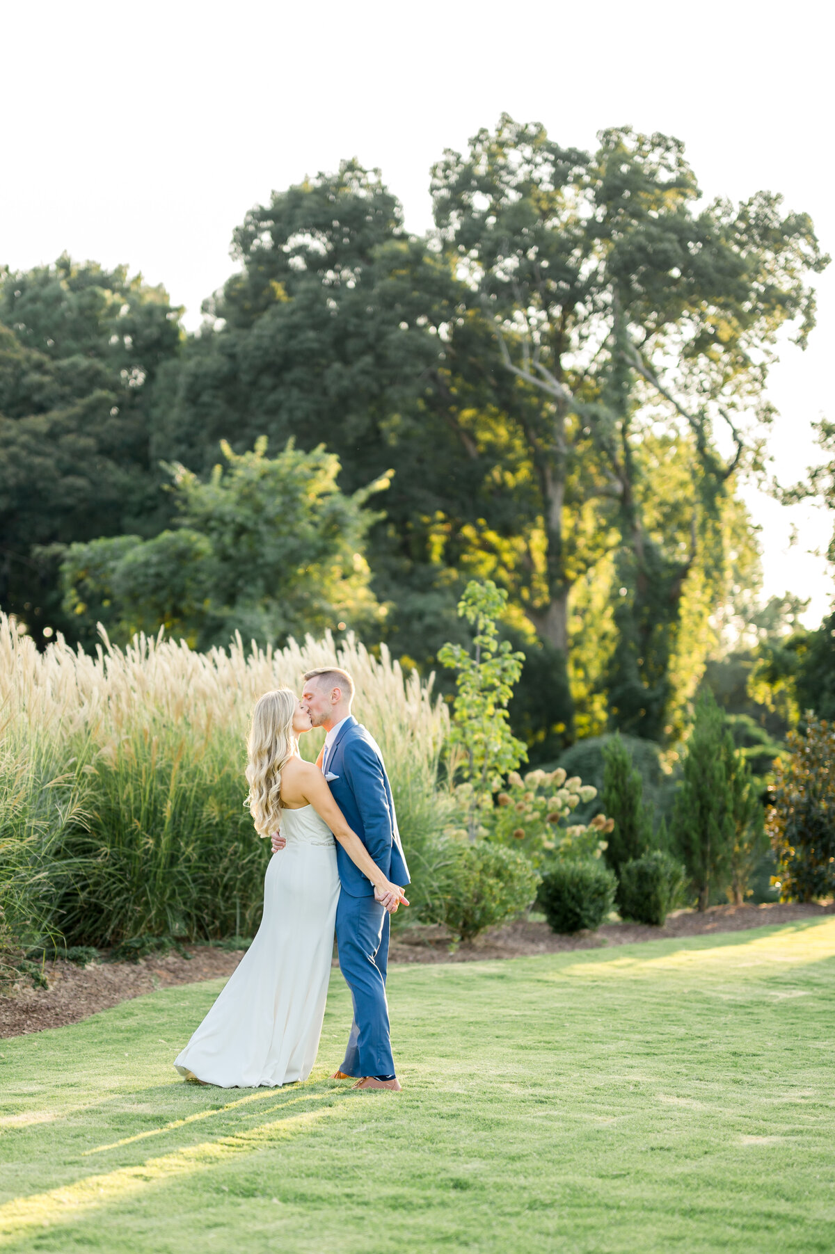 bride in white and groom in blue on lawn