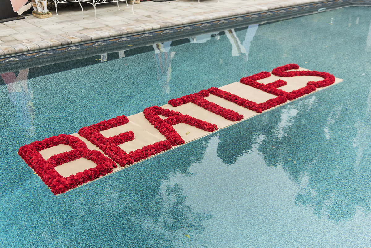 A Beatles sign made of red carnations floats in a pool