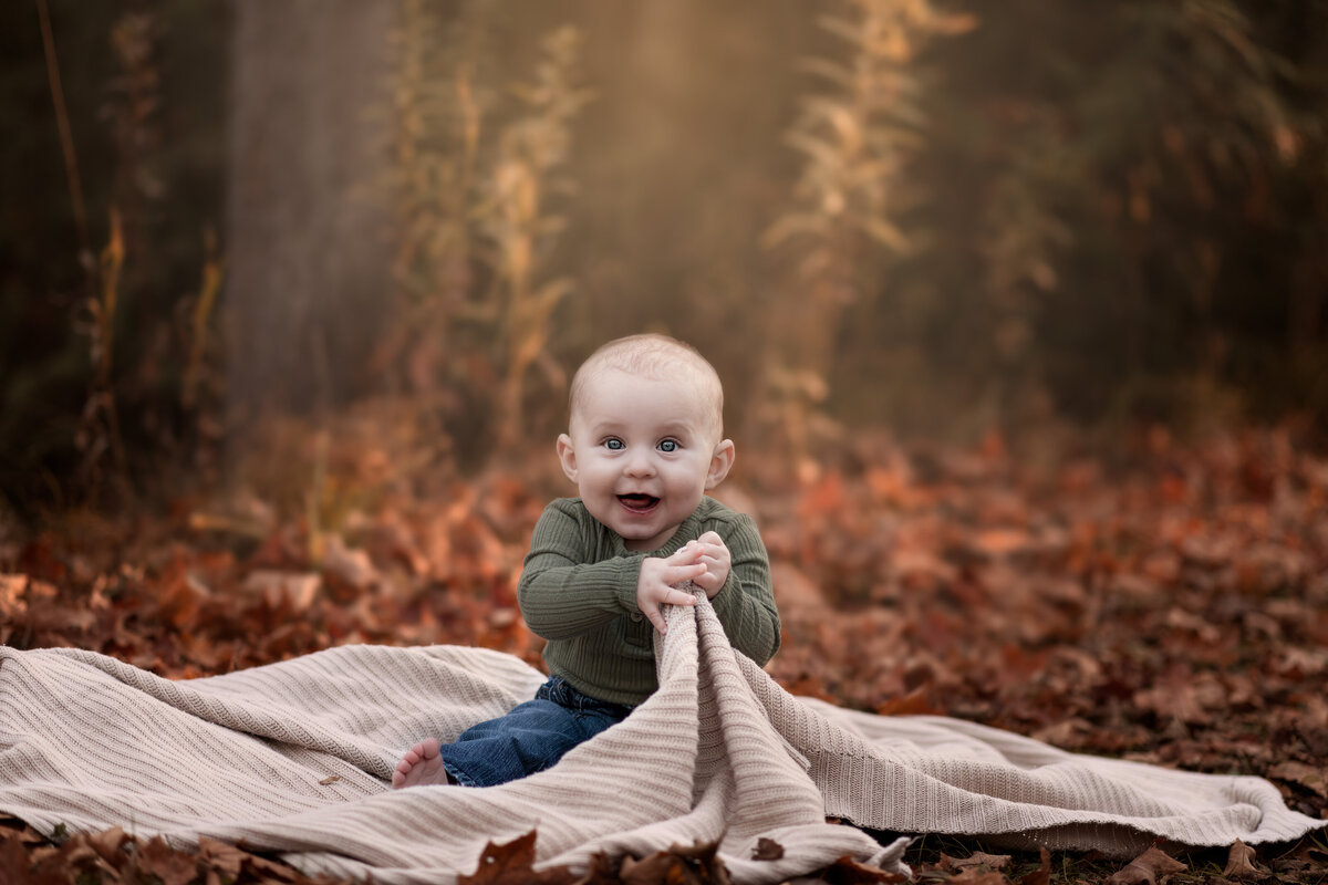A cozy autumn milestone photo of a smiling baby in Ayr, Ontario—capturing nature’s warmth and childhood wonder in the fall.