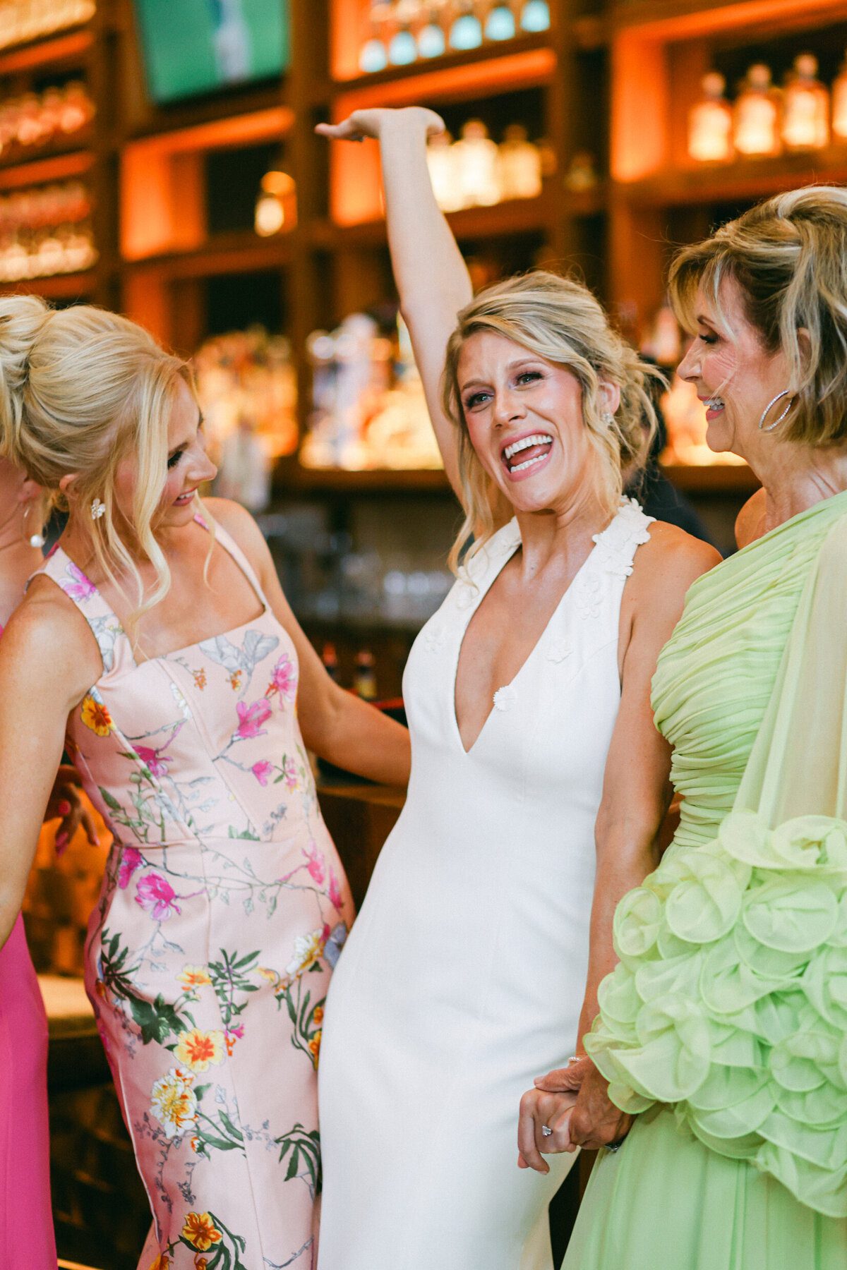 A wedding photo of a bride in her white dress with her bridesmiads who are wearing different colored bright dresses