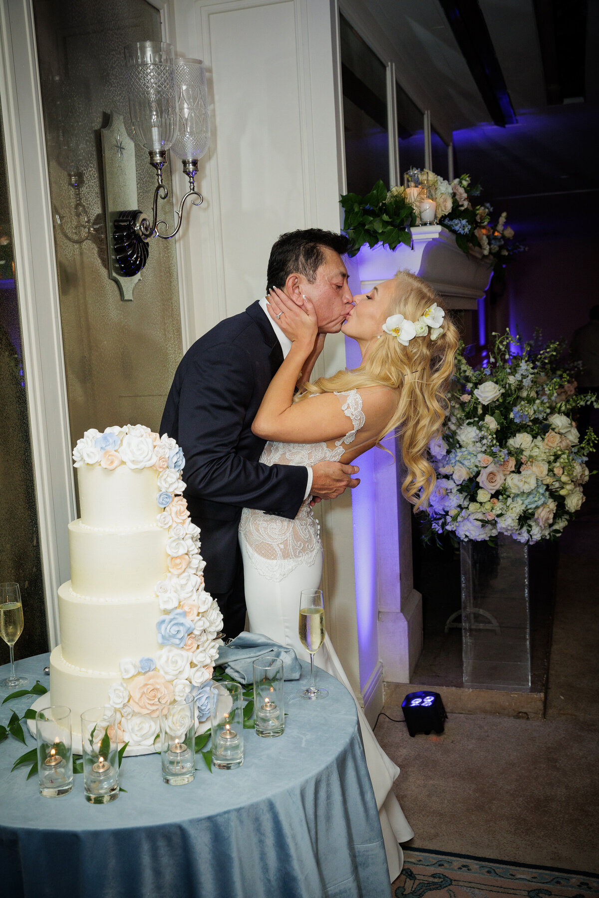 A bride and groom kissing in front of a wedding cake