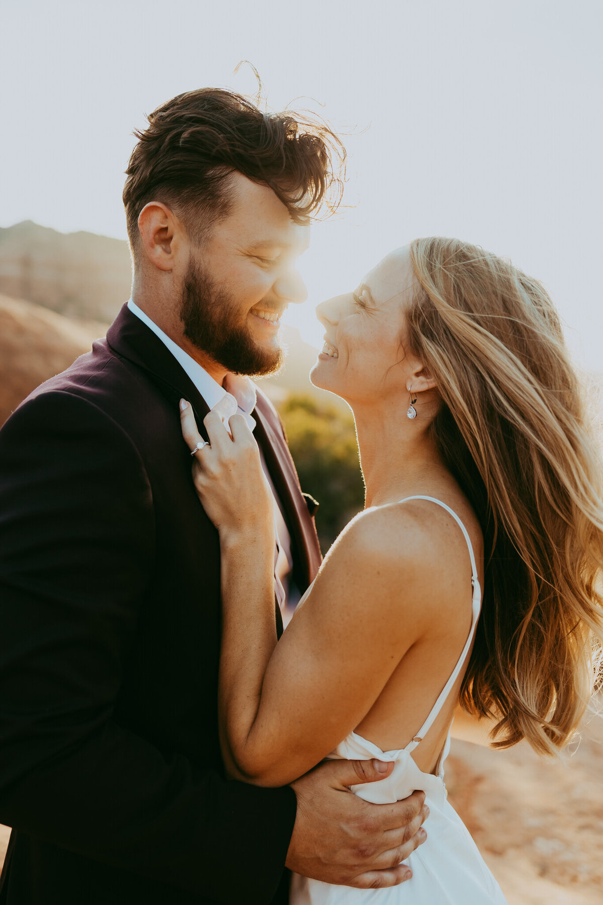 couple smiles with sunshine behind them