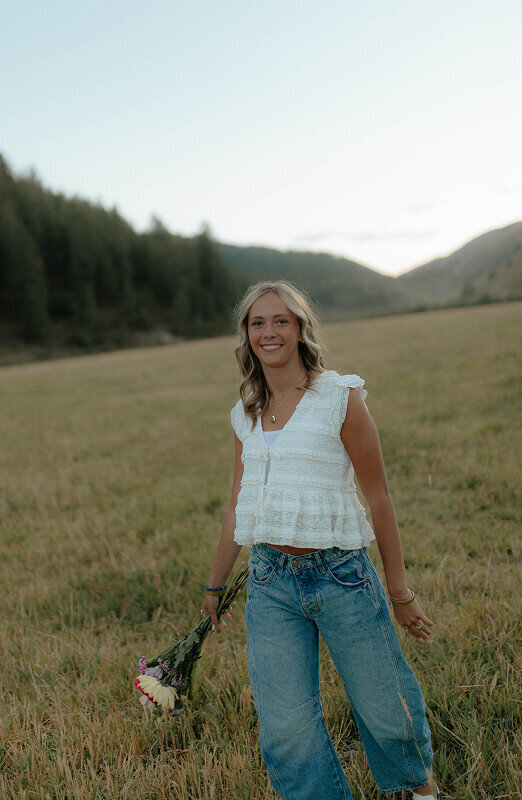 A girl smiles at her senior portrait photographer Brittney Ann Photography. The photo is slightly tilted making it feel casual and fun.