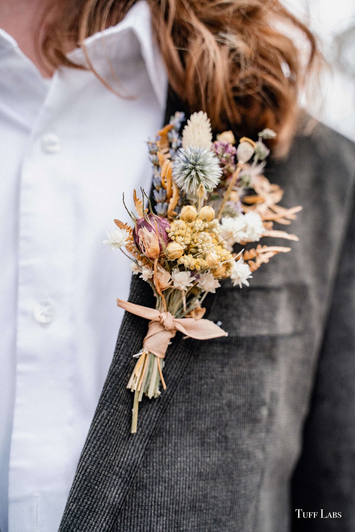 Dried floral boutonniere by Flowers and Thyme pinned on suit.