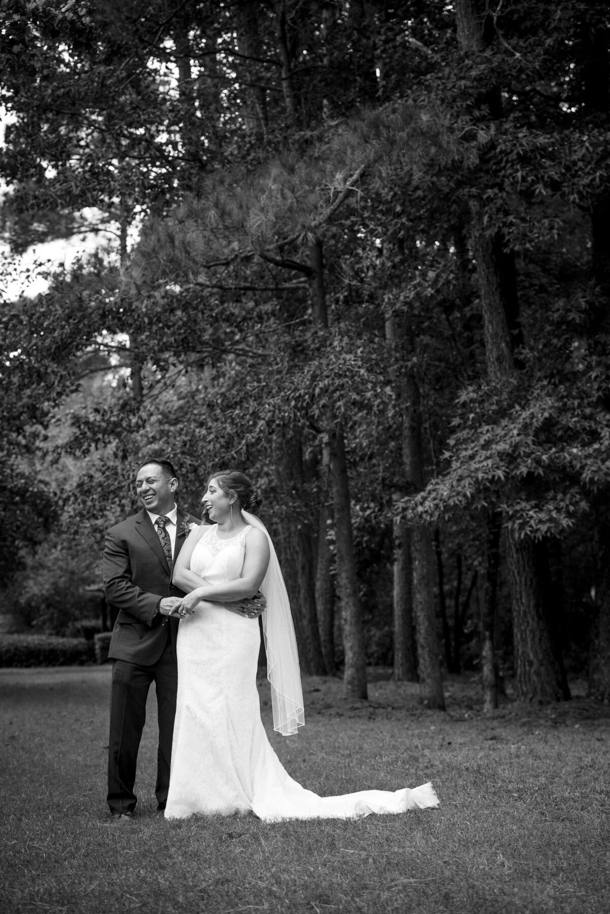 Black and white image of a bride and groom laughing while holding hands in Raleigh NC by Charlotte wedding photographers DeLong Photography